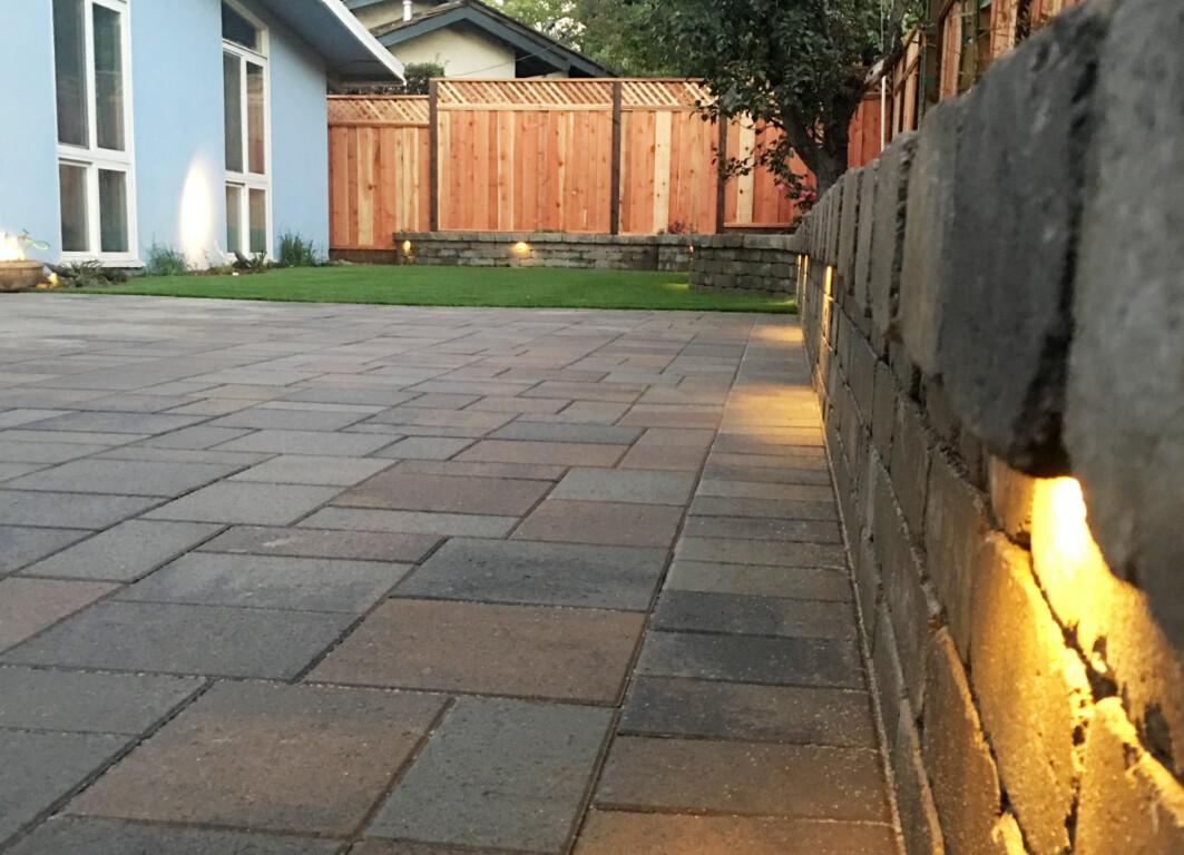 Beautiful stamped concrete patio with integrated landscape lighting at dusk